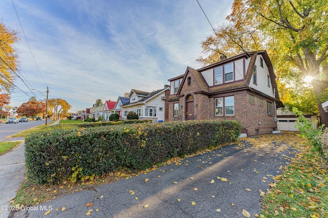 view of front of home featuring brick siding, a gambrel roof, and a chimney