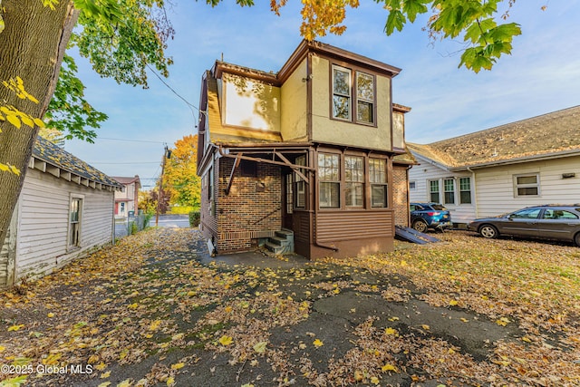 rear view of house with entry steps and stucco siding