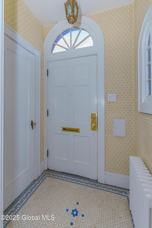 entrance foyer with baseboards, radiator heating unit, and wallpapered walls