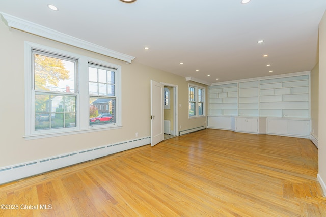 unfurnished room with a wealth of natural light, a baseboard heating unit, and light wood-style flooring