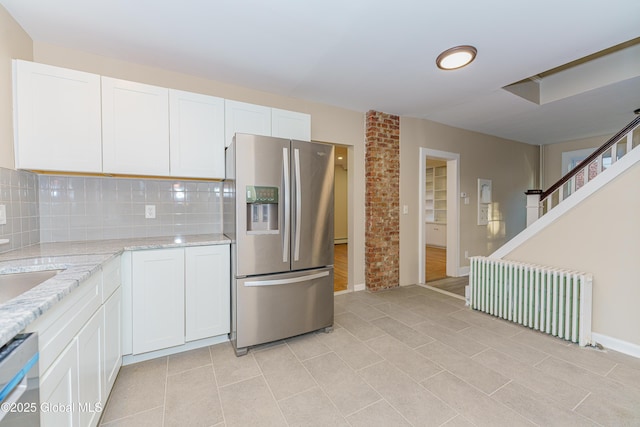 kitchen with decorative backsplash, white cabinets, radiator, and stainless steel appliances