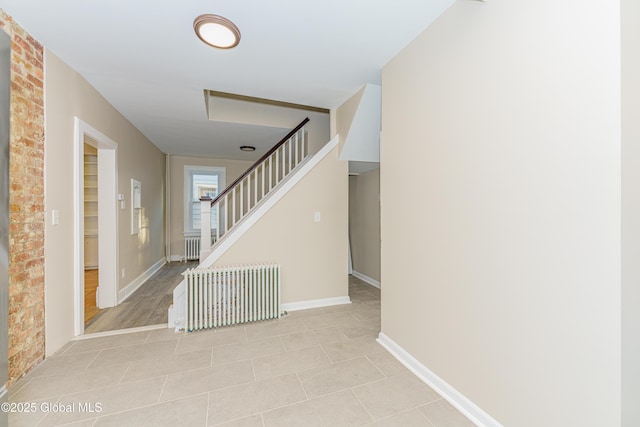 stairway featuring tile patterned flooring, radiator, and baseboards