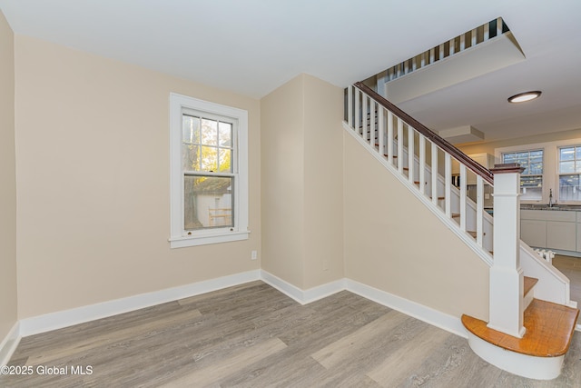 staircase featuring wood finished floors, baseboards, and a wealth of natural light