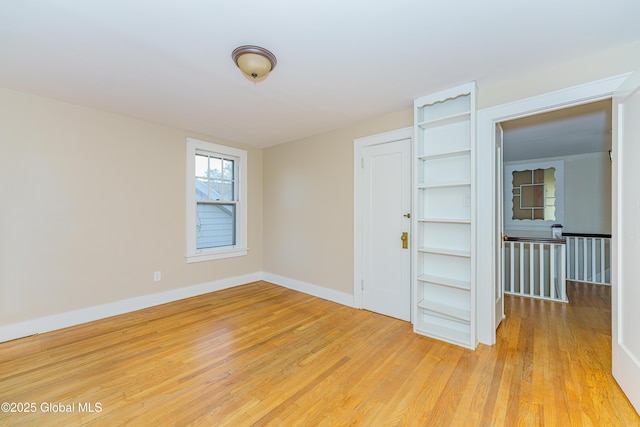 empty room featuring baseboards and light wood finished floors