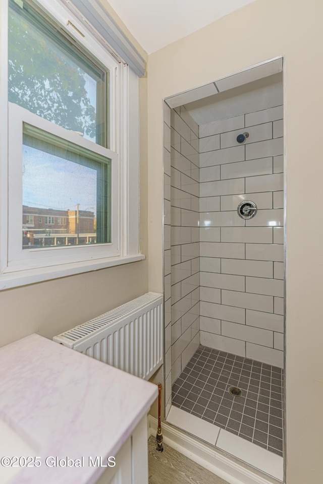 full bathroom featuring a healthy amount of sunlight, a shower stall, and radiator heating unit