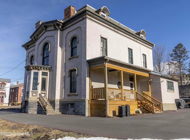 47 Church St, Amsterdam, NY 12010 - view of front of home featuring stucco siding, a chimney, and covered porch