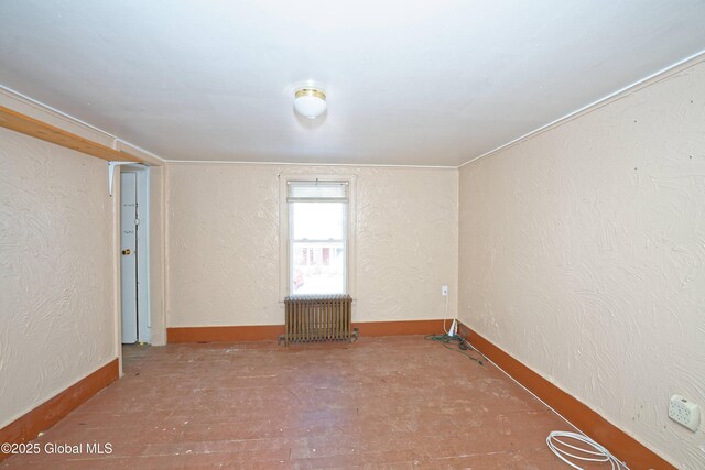 spare room featuring radiator and a textured wall