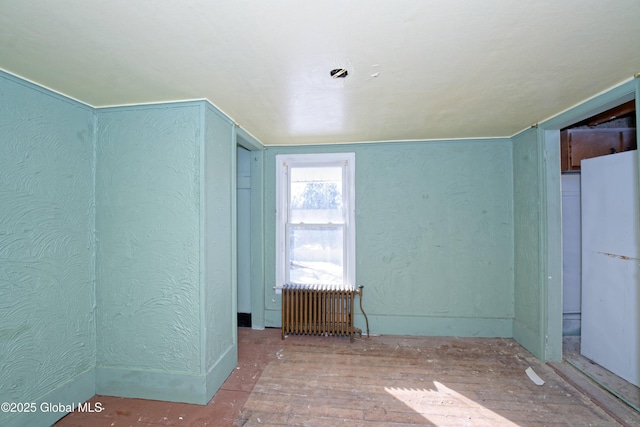 unfurnished room featuring radiator heating unit and a textured wall