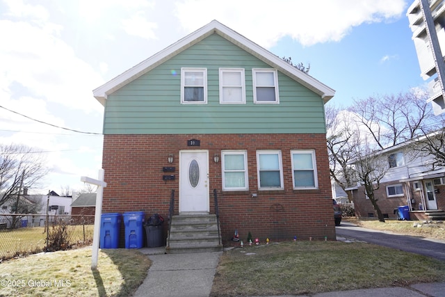 view of front of home featuring fence, brick siding, a front lawn, and entry steps