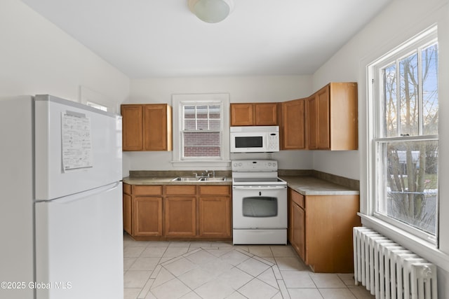 kitchen with brown cabinets, white appliances, radiator heating unit, and a sink