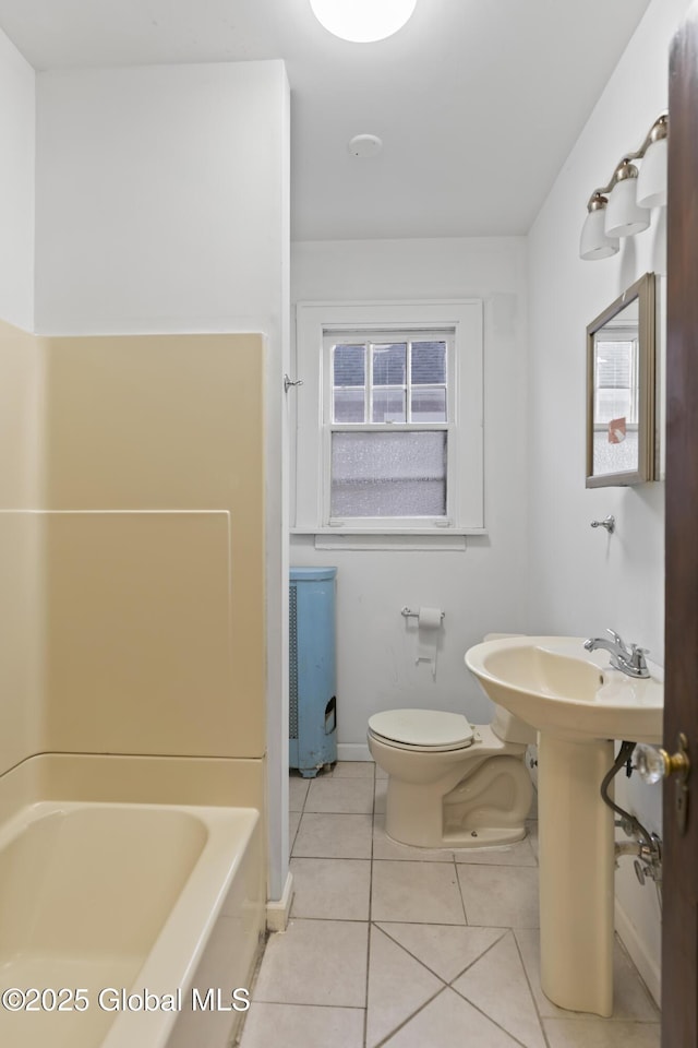 bathroom featuring tile patterned flooring, toilet, a healthy amount of sunlight, and baseboards