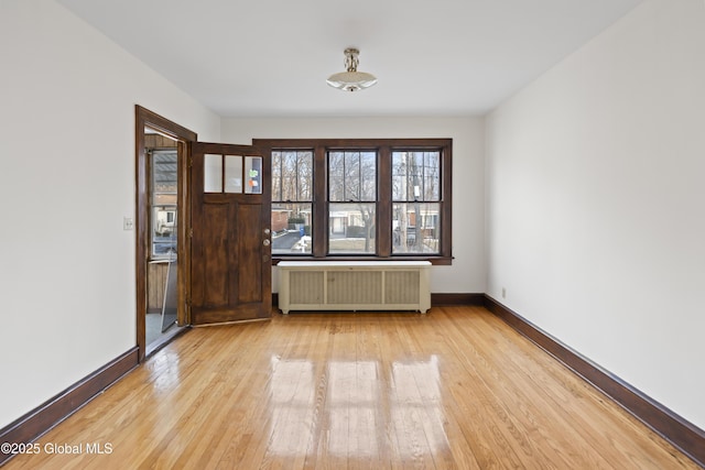 unfurnished room with radiator, baseboards, and hardwood / wood-style floors