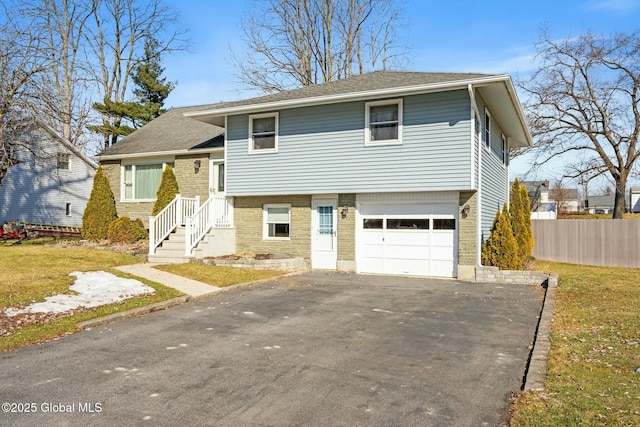 tri-level home featuring aphalt driveway, fence, and a garage