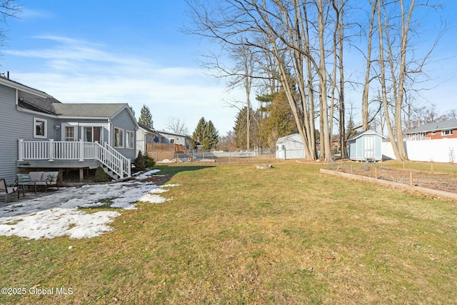 view of yard with a deck, an outdoor structure, a storage unit, and a fenced backyard