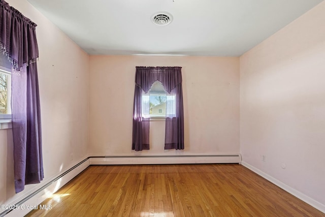 spare room featuring visible vents, baseboards, baseboard heating, and wood finished floors