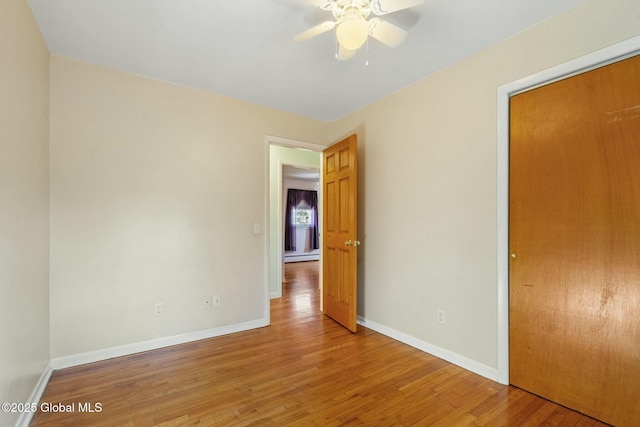 unfurnished bedroom featuring a baseboard heating unit, baseboards, and wood finished floors