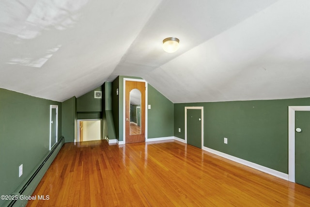 additional living space featuring vaulted ceiling, wood finished floors, baseboards, and a baseboard radiator