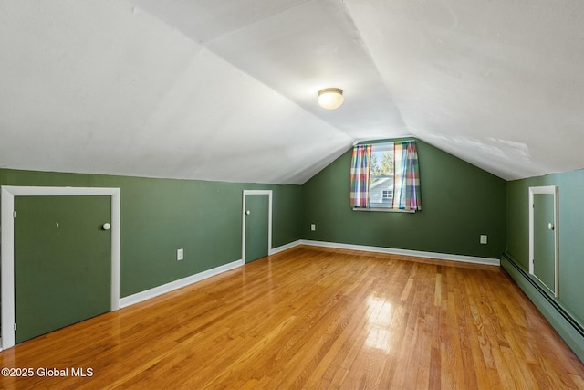 bonus room featuring light wood finished floors, baseboards, lofted ceiling, and a baseboard radiator