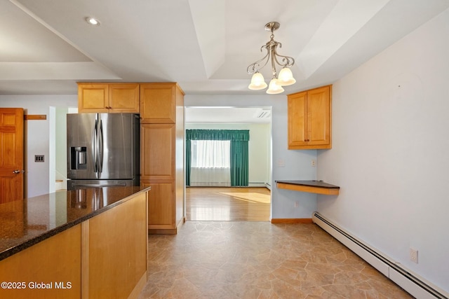 kitchen with stainless steel refrigerator with ice dispenser, dark stone countertops, built in desk, a raised ceiling, and baseboard heating