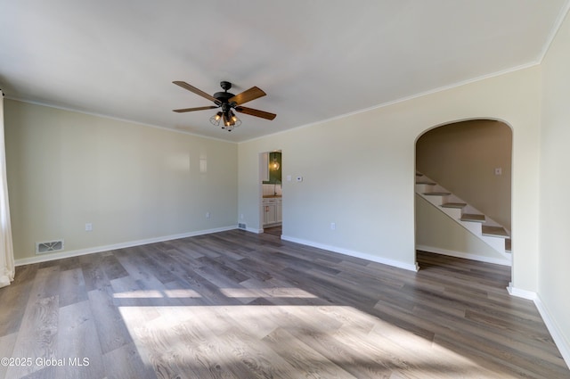 empty room featuring wood finished floors, arched walkways, visible vents, and ceiling fan