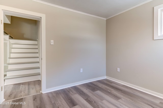 empty room featuring wood finished floors, baseboards, and ornamental molding