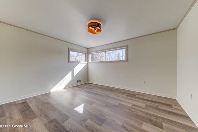 unfurnished room featuring visible vents, baseboards, wood finished floors, and crown molding