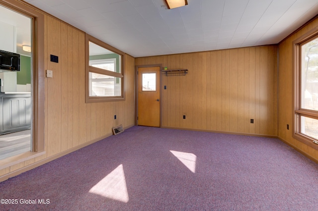 empty room featuring a wealth of natural light, baseboards, visible vents, and carpet floors