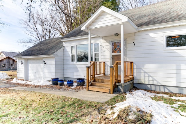 view of exterior entry featuring a shingled roof and a garage