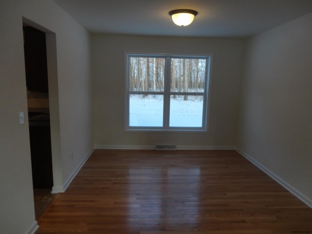 unfurnished room with wood finished floors, visible vents, and baseboards