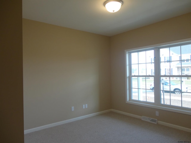 spare room featuring visible vents, baseboards, and light carpet