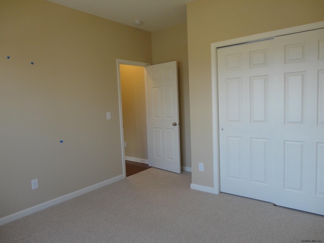 unfurnished bedroom with a closet, baseboards, and carpet flooring