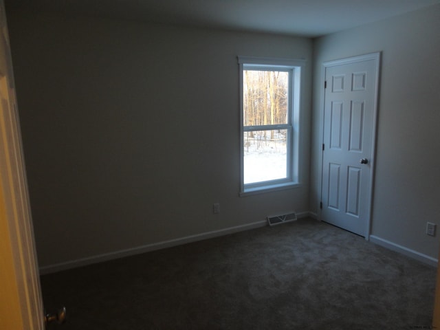 empty room with visible vents, baseboards, and dark colored carpet