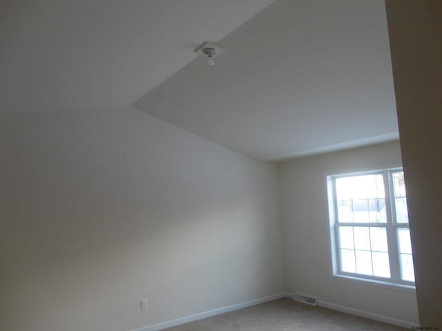 unfurnished room with lofted ceiling, baseboards, visible vents, and light carpet