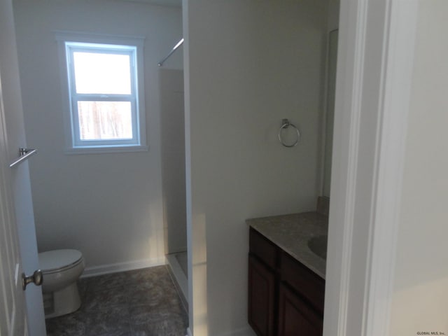 full bathroom with baseboards, a shower stall, vanity, and toilet