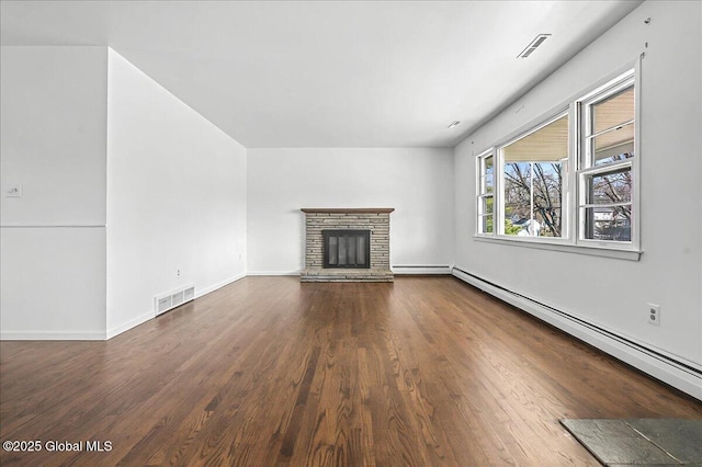 unfurnished living room featuring visible vents, a stone fireplace, wood finished floors, and a baseboard radiator