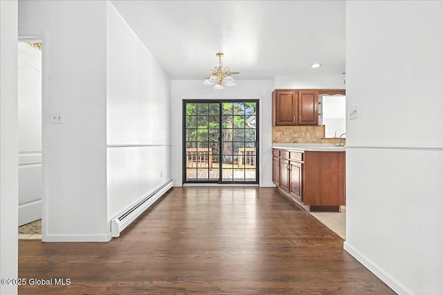 unfurnished dining area featuring dark wood finished floors, a notable chandelier, baseboards, and baseboard heating