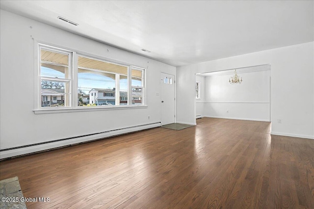 unfurnished living room with wood finished floors, baseboards, visible vents, baseboard heating, and a chandelier