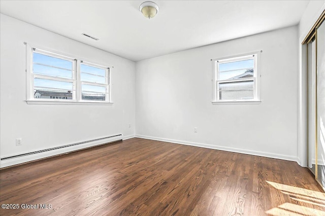 unfurnished bedroom featuring dark wood-style floors, baseboards, visible vents, a baseboard radiator, and a closet