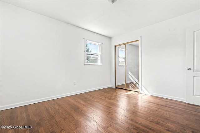 unfurnished bedroom with wood finished floors, baseboards, and a closet