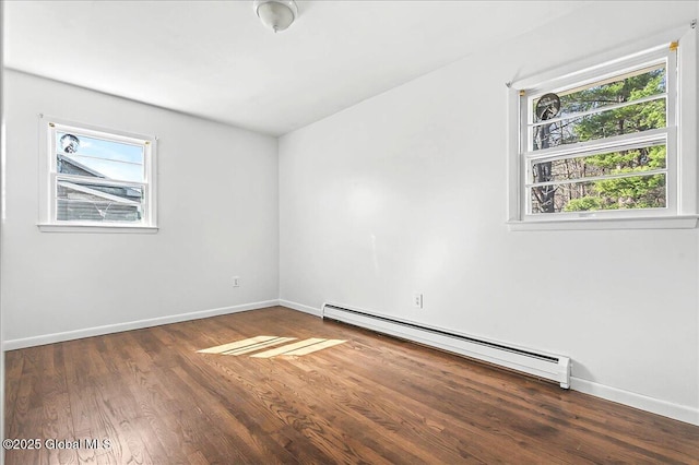 empty room with a baseboard heating unit, baseboards, and wood finished floors