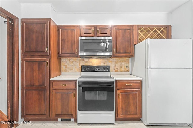 kitchen featuring stainless steel microwave, backsplash, light countertops, electric range oven, and freestanding refrigerator