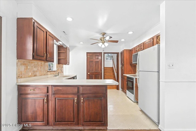 kitchen with white appliances, a ceiling fan, a peninsula, light countertops, and tasteful backsplash