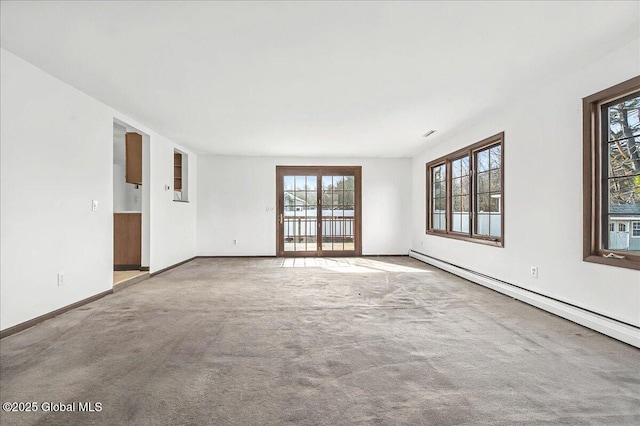 empty room featuring a baseboard heating unit, baseboards, and carpet floors