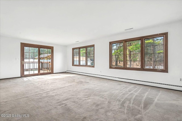 carpeted spare room featuring baseboard heating and visible vents