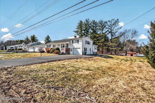 view of front of home featuring aphalt driveway, an attached garage, and a front lawn