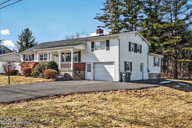 tri-level home with aphalt driveway, a porch, a chimney, and an attached garage