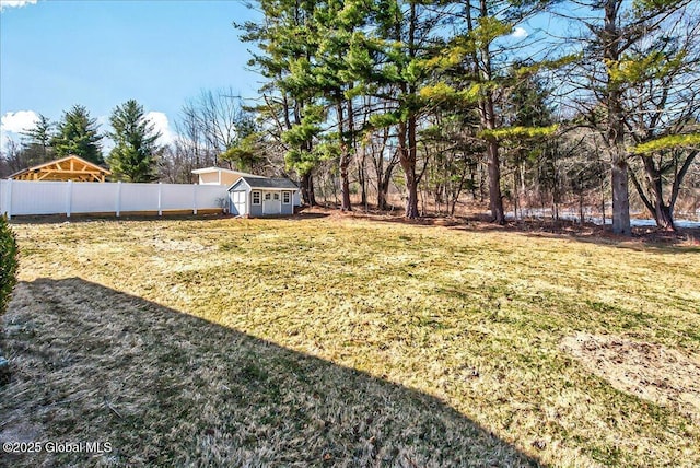 view of yard featuring a storage shed, an outdoor structure, and fence