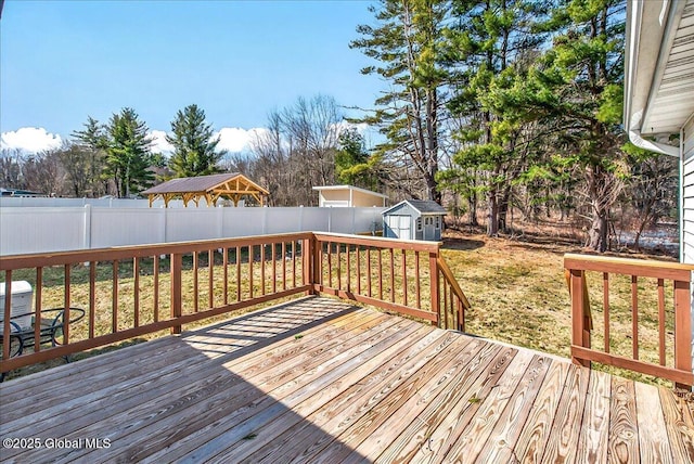 wooden terrace with a storage unit, an outbuilding, and a fenced backyard