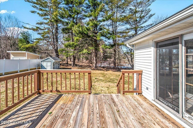 wooden terrace with an outbuilding, a storage unit, fence, and a lawn