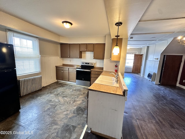 kitchen with stainless steel electric range oven, a wainscoted wall, radiator heating unit, freestanding refrigerator, and a sink